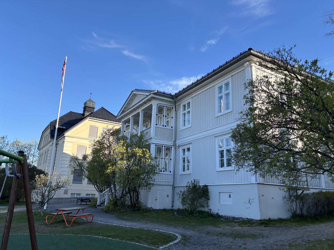et hvitt hus med plen og trær foran seg