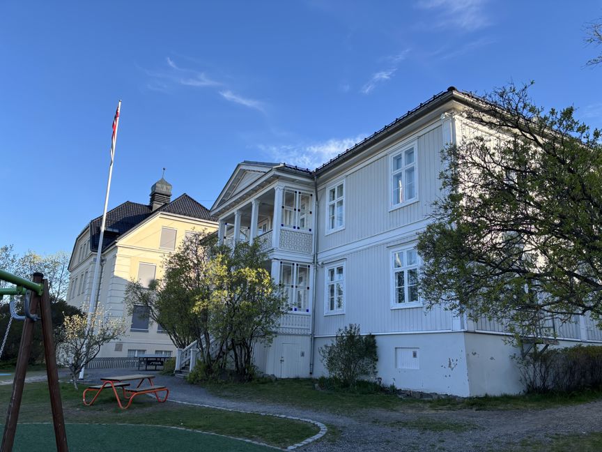 et hvitt hus med plen og trær foran seg