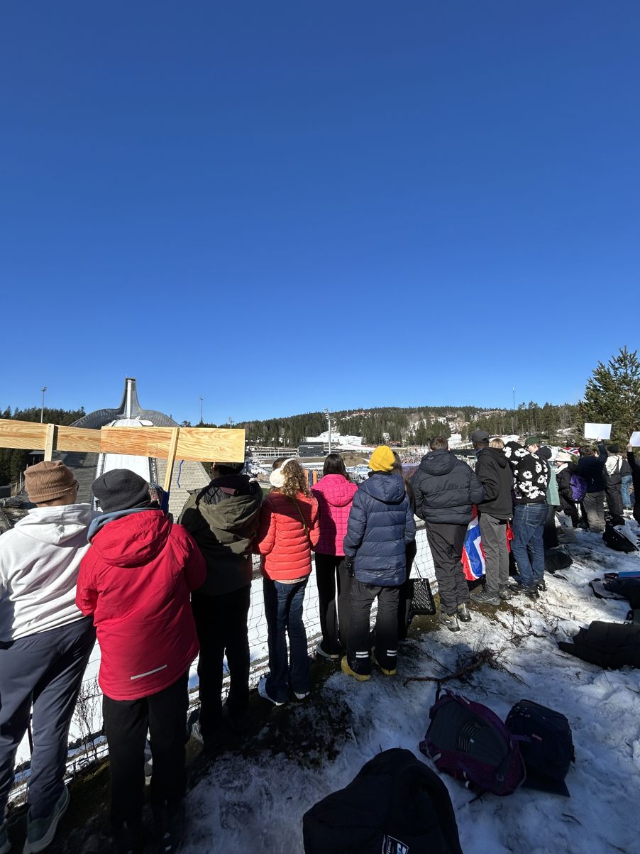 En gruppe mennesker som står på en snødekt ås En gruppe mennesker som står på en snødekt ås
