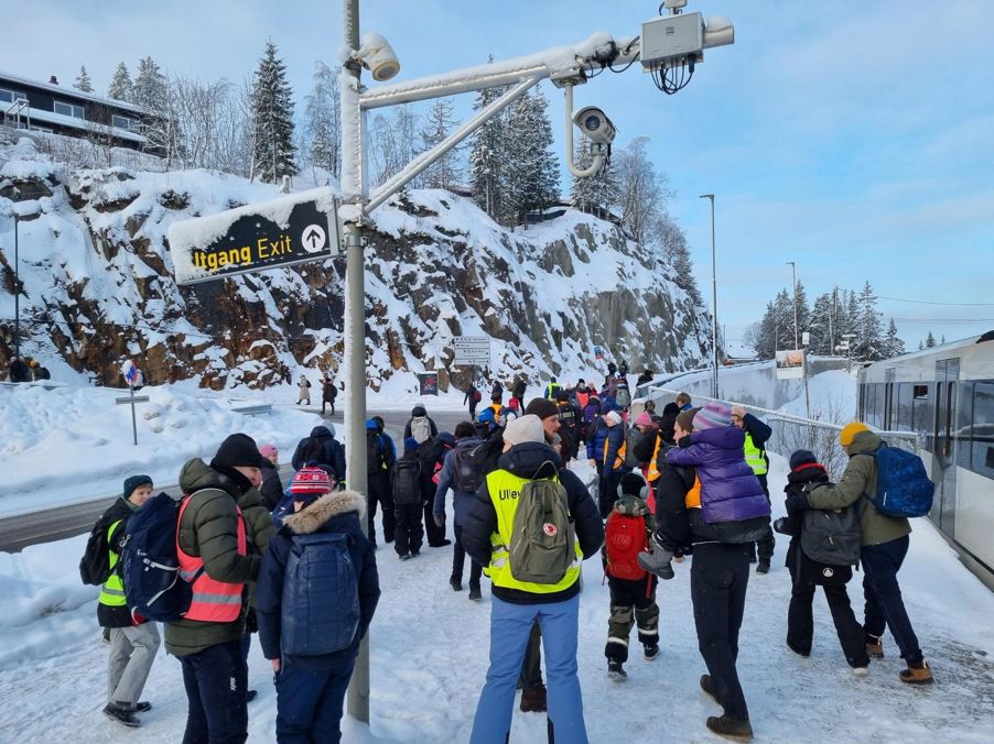 En gruppe mennesker som står på en snødekt ås En gruppe mennesker som står på en snødekt ås