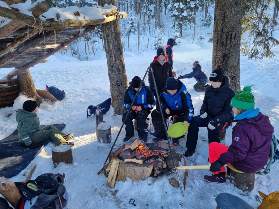 En gruppe mennesker som sitter på en snødekt ås med et tre En gruppe mennesker som sitter på en snødekt ås med et tre